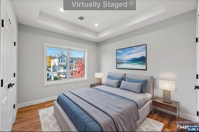 bedroom with a tray ceiling and hardwood / wood-style floors