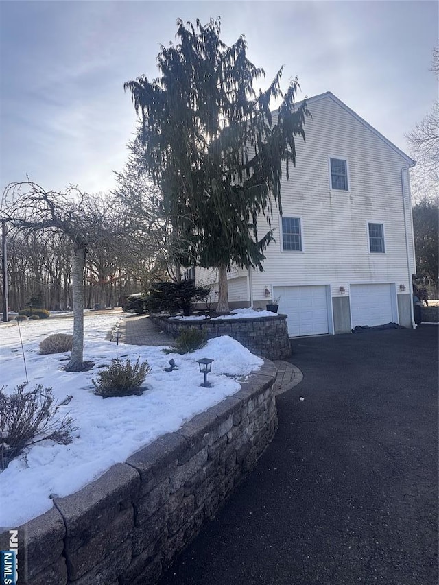 view of snowy exterior featuring a garage