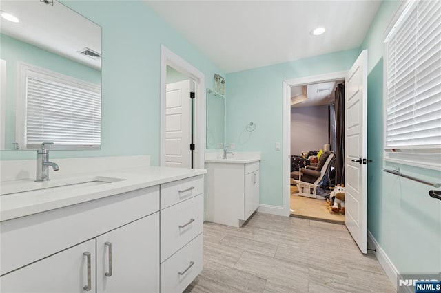 bathroom featuring baseboards, visible vents, two vanities, a sink, and recessed lighting