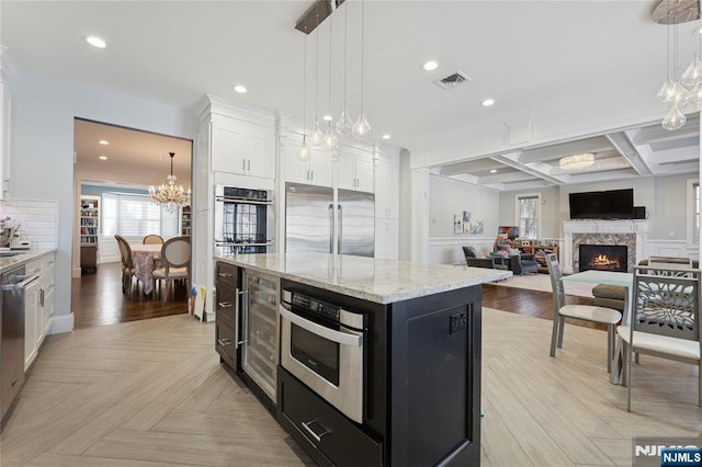 kitchen with visible vents, white cabinets, a center island, hanging light fixtures, and stainless steel appliances