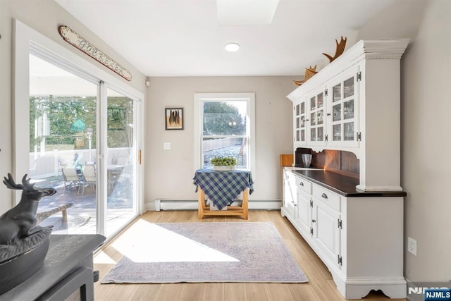 entryway with light wood-type flooring, a skylight, and baseboard heating