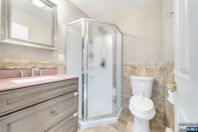 bathroom featuring an enclosed shower, tile patterned floors, toilet, tile walls, and vanity