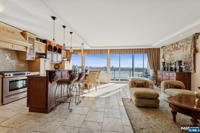 kitchen with dark countertops, a water view, hanging light fixtures, glass insert cabinets, and gas stove