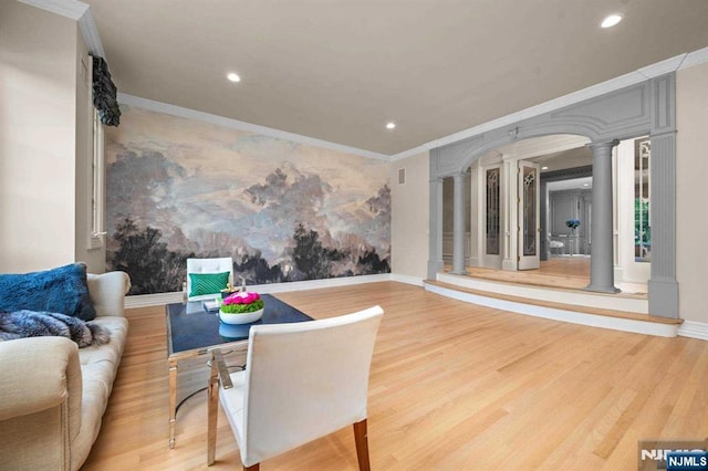 sitting room with hardwood / wood-style floors, crown molding, and decorative columns