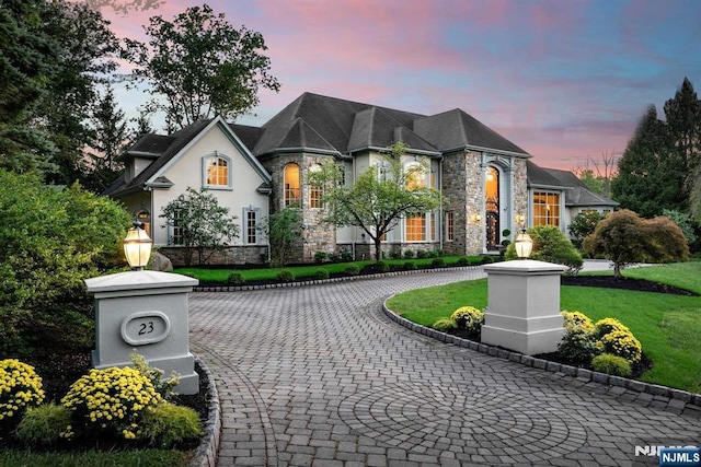 french country inspired facade featuring a yard