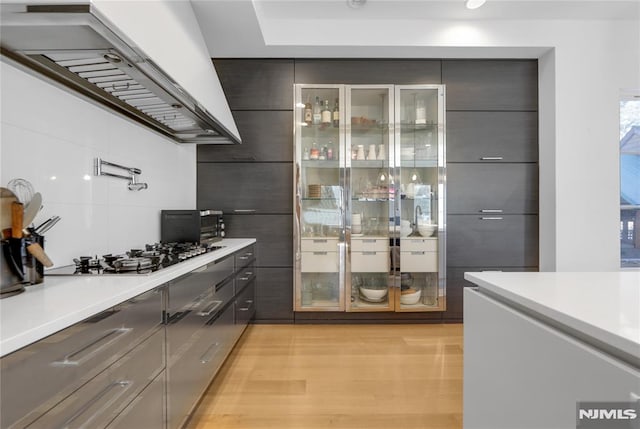 interior space with premium range hood, a toaster, stainless steel gas cooktop, and light wood finished floors