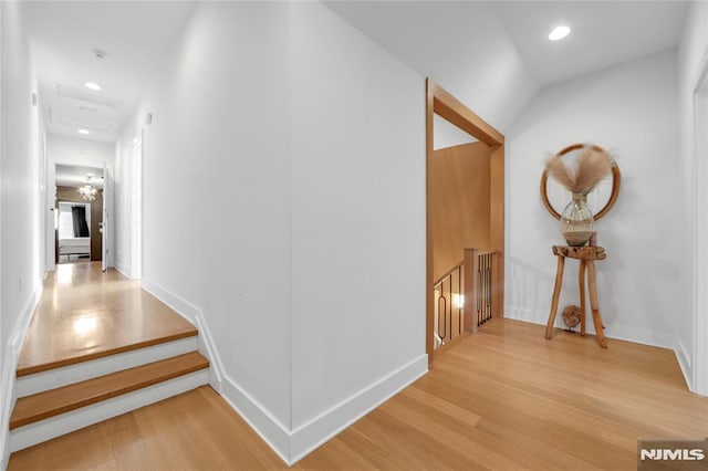 hallway featuring recessed lighting, baseboards, wood finished floors, and an upstairs landing