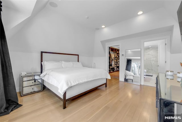 bedroom featuring connected bathroom, a walk in closet, wood finished floors, and recessed lighting