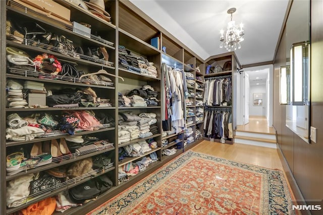 walk in closet featuring an inviting chandelier and wood finished floors