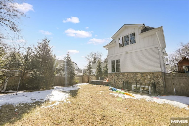 view of home's exterior featuring fence, stone siding, and board and batten siding