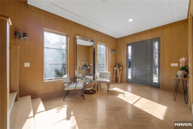 foyer entrance featuring wood walls, baseboards, and ornamental molding