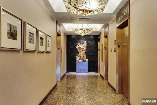 hallway with speckled floor, elevator, visible vents, and baseboards