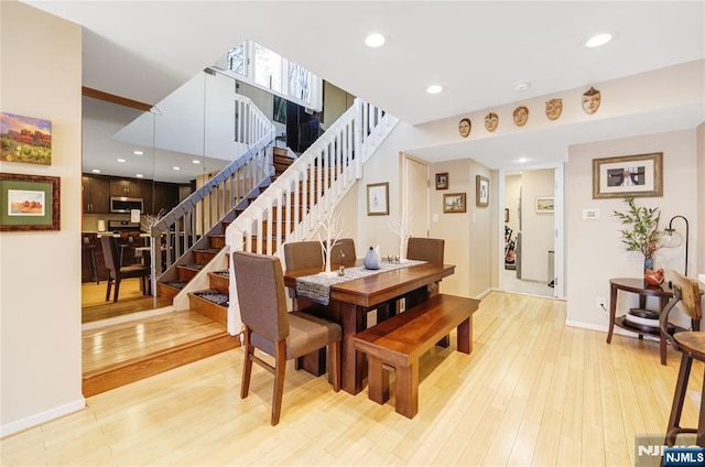 dining area with light wood-type flooring, stairway, baseboards, and recessed lighting