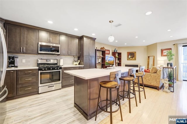 kitchen with stainless steel appliances, tasteful backsplash, light countertops, and dark brown cabinetry