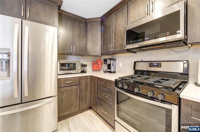 kitchen featuring a toaster, light countertops, backsplash, appliances with stainless steel finishes, and dark brown cabinetry