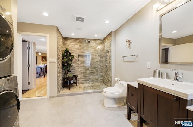 full bath with toilet, stacked washer / dryer, vanity, visible vents, and a stall shower