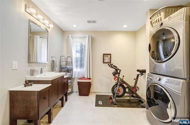 laundry area with light tile patterned floors, visible vents, stacked washer / dryer, a sink, and laundry area