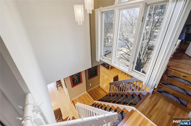 stairway with wood finished floors and a notable chandelier