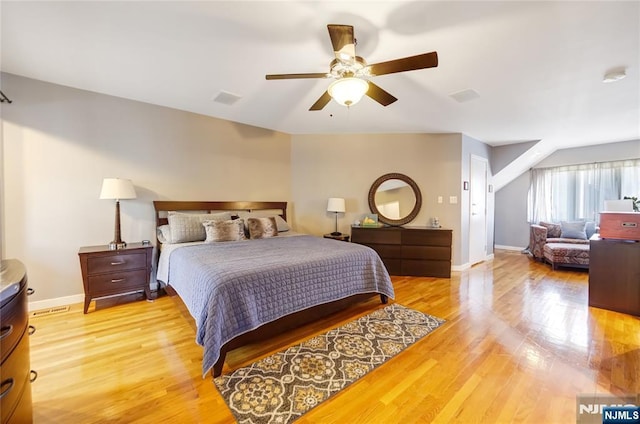 bedroom with ceiling fan, visible vents, light wood-style flooring, and baseboards