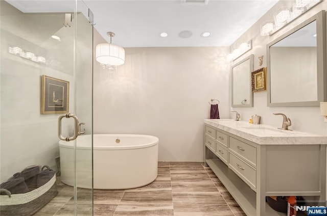 bathroom with double vanity, a soaking tub, a sink, and wood tiled floor