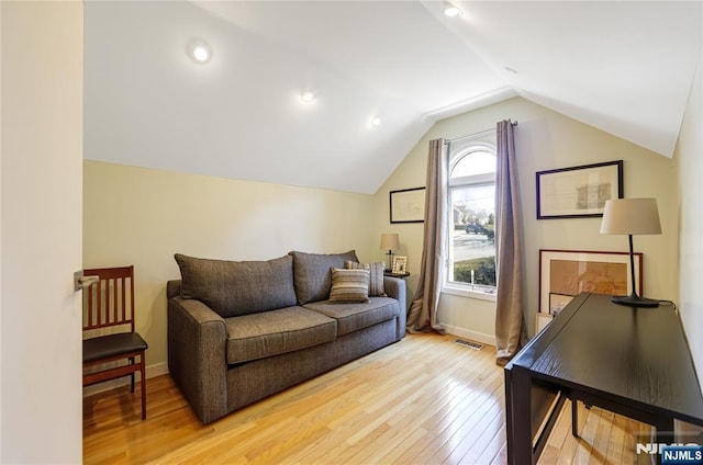 living room with lofted ceiling, light wood-type flooring, visible vents, and baseboards