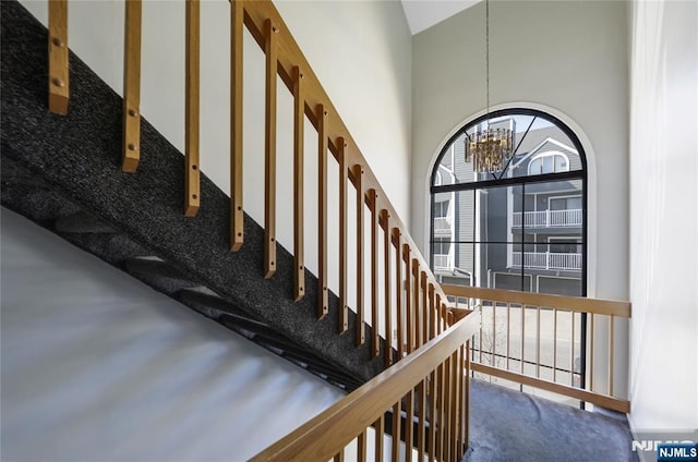 stairs with a notable chandelier and a high ceiling