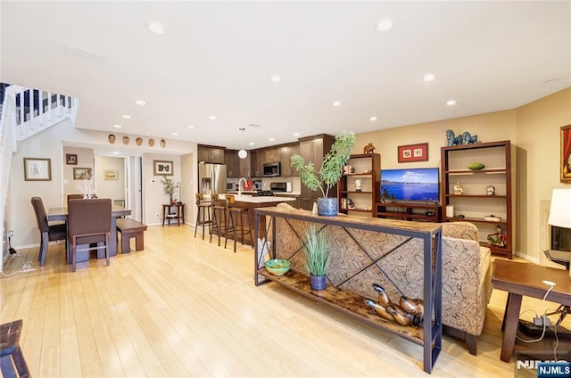 living room featuring stairs, light wood-type flooring, baseboards, and recessed lighting