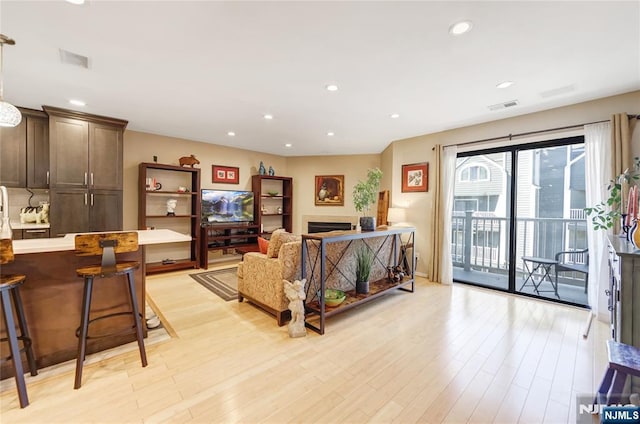 living area with light wood-style floors, a fireplace, visible vents, and recessed lighting