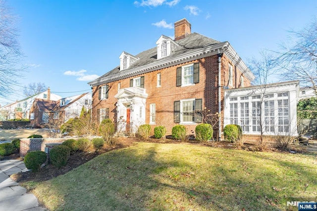 colonial inspired home with a front yard and a sunroom