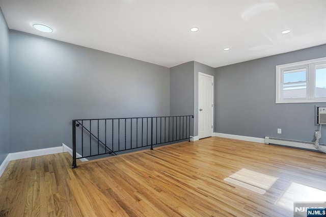 spare room with light wood-type flooring and a baseboard heating unit