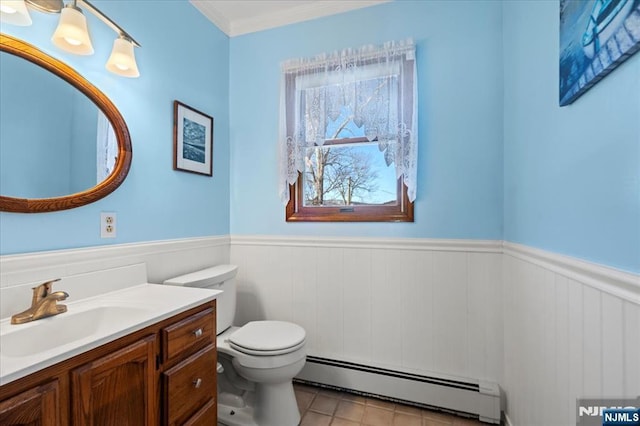 bathroom featuring toilet, a baseboard heating unit, vanity, wainscoting, and crown molding