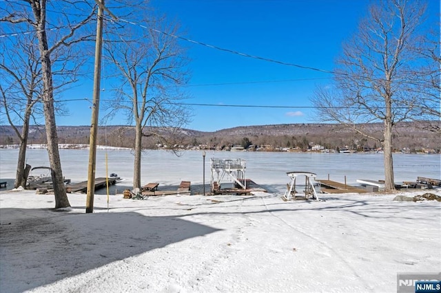 yard covered in snow featuring a water view