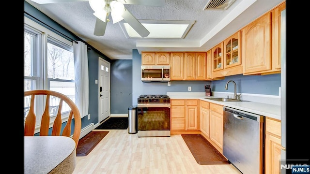 kitchen with a sink, visible vents, light countertops, appliances with stainless steel finishes, and glass insert cabinets