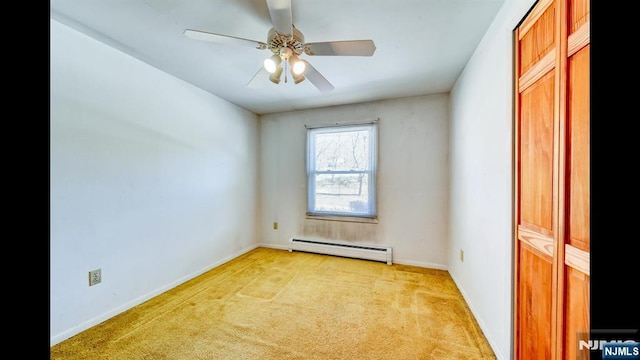 empty room with light carpet, ceiling fan, baseboard heating, and baseboards