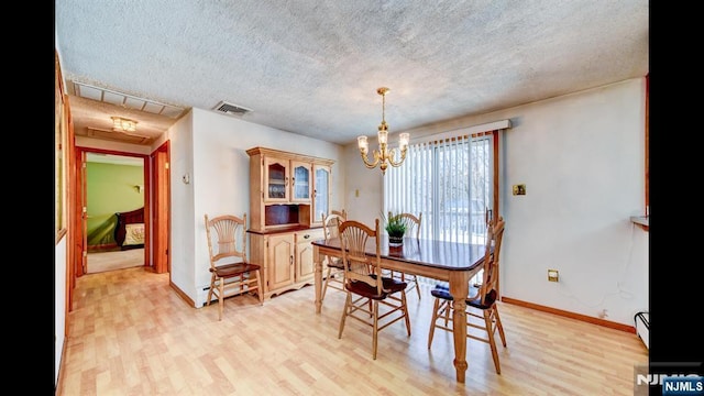 dining room with a baseboard radiator, visible vents, an inviting chandelier, light wood-style floors, and a textured ceiling