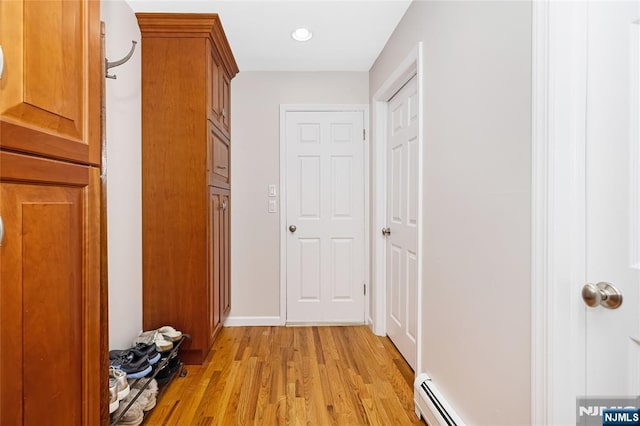 hallway featuring light wood finished floors and a baseboard radiator