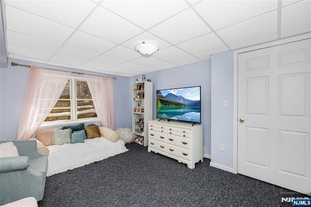 living area with dark carpet and a paneled ceiling