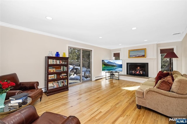 living room featuring a warm lit fireplace, visible vents, crown molding, light wood-style floors, and recessed lighting