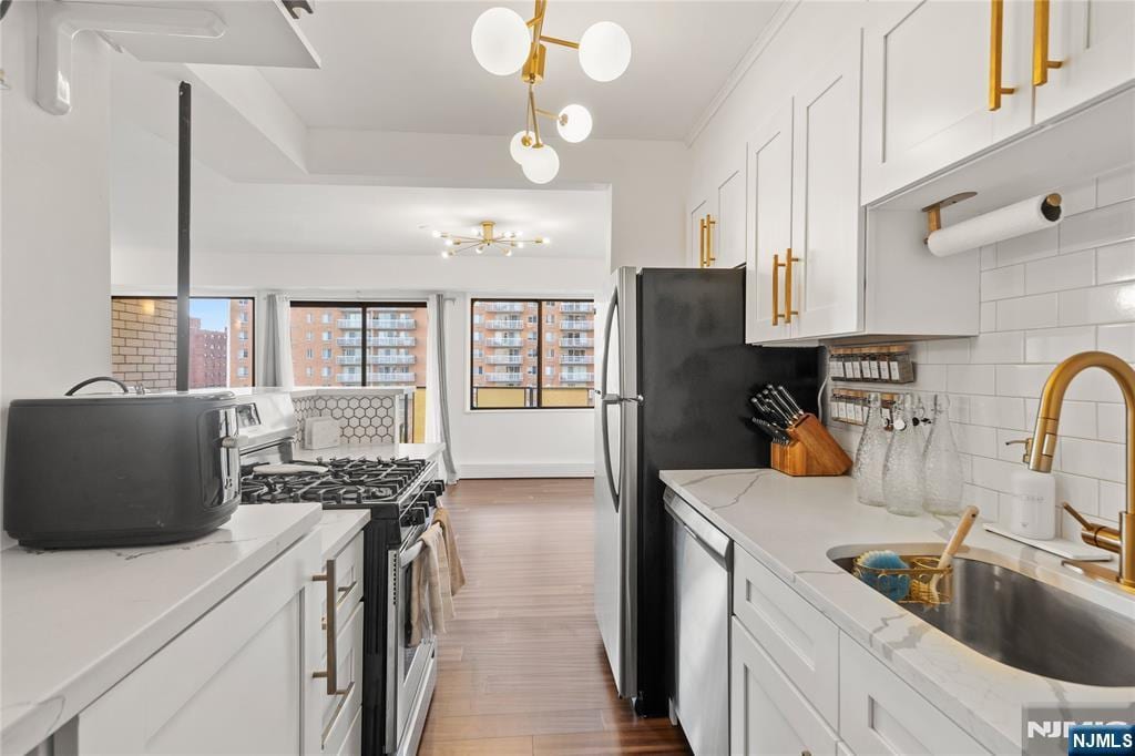 kitchen featuring white cabinets, appliances with stainless steel finishes, sink, and light stone countertops