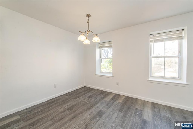 unfurnished room featuring dark wood-type flooring and a chandelier