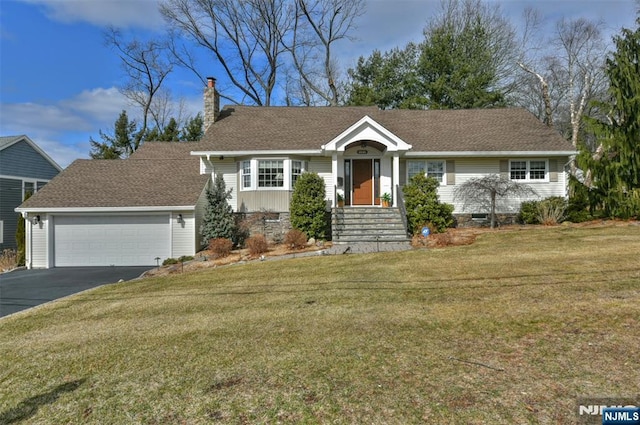 ranch-style home featuring a front yard, roof with shingles, a chimney, driveway, and an attached garage