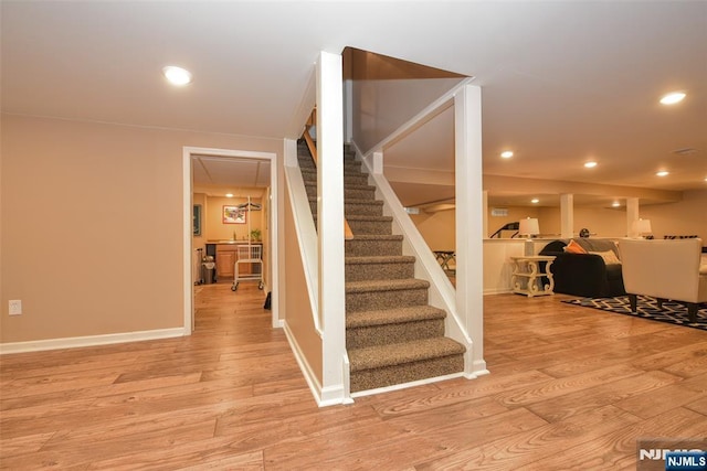 stairway featuring recessed lighting, wood finished floors, and baseboards