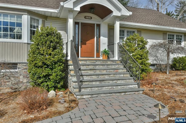 entrance to property featuring roof with shingles