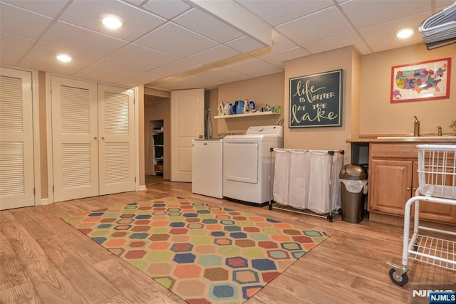 laundry room with a sink, light wood-style floors, cabinet space, and separate washer and dryer