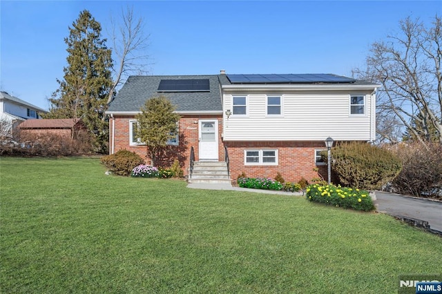 view of front facade with a front lawn and solar panels