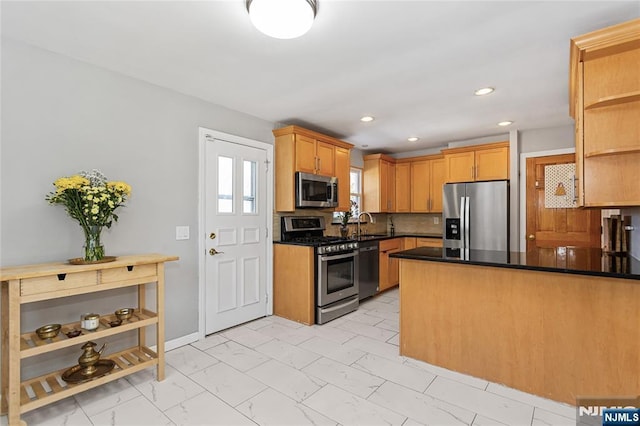 kitchen featuring appliances with stainless steel finishes, tasteful backsplash, and kitchen peninsula