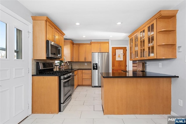 kitchen with sink, kitchen peninsula, stainless steel appliances, and decorative backsplash