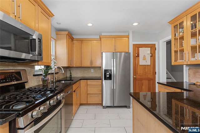 kitchen featuring dark stone counters, backsplash, appliances with stainless steel finishes, and sink