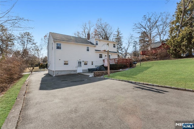 back of property with a lawn and a deck