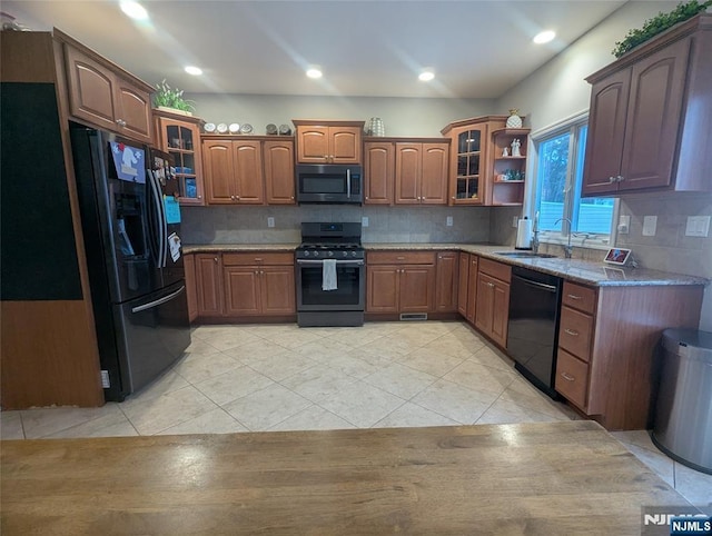 kitchen with refrigerator, gas stove, light tile patterned floors, sink, and black dishwasher